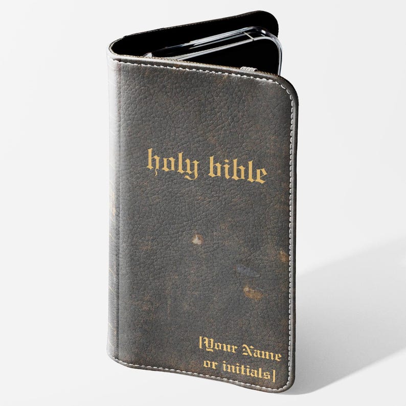 May include: A dark brown leather phone case with the words "holy bible" in gold lettering. The case has a distressed look and a white stitched border. The bottom of the case reads "[Your Name or initials]"