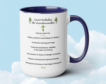 Op de afbeelding: Een witte keramische mok met een blauwe rand en handvat. De mok heeft een ontwerp met de tekst "Sint Nicolaas de Wonderwerker" en een lijst met de beschermheiligen van de heilige, waaronder veiligheid, gezondheid en welzijn van kinderen, bescherming tijdens reizen, financiële hulp en zegeningen in het huwelijk en gezinsleven.