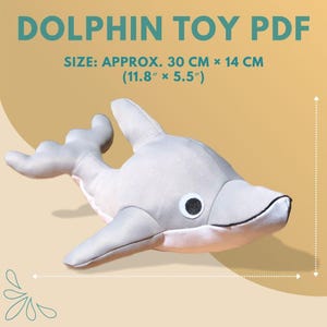 Puede incluir: Un juguete de delfín gris con ojos negros y blancos. El texto "DOLPHIN TOY PDF" es visible. Tamaño aproximado: 30 cm x 14 cm.