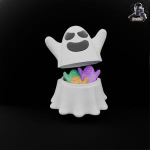 Könnte beinhalten: Ein weißer, geisterförmiger Behälter mit einem lächelnden Gesicht, der bunte, geisterförmige Süßigkeiten enthält. Der Deckel des Behälters ist geöffnet und gibt den Blick auf die Leckereien frei. Der Hintergrund ist schwarz.