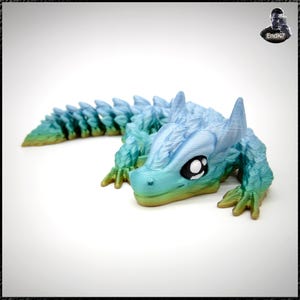 May include: A 3D-printed articulated dragon toy in shades of blue, green, and yellow. The dragon has large, expressive eyes and a segmented body. The toy is designed to be poseable and flexible, with a detailed, textured surface.