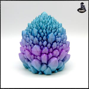 May include: A decorative, geometric object in the shape of a crystal cluster. The object transitions from a blue hue at the top to a purple color at the base. The surface is composed of many individual, pointed facets.
