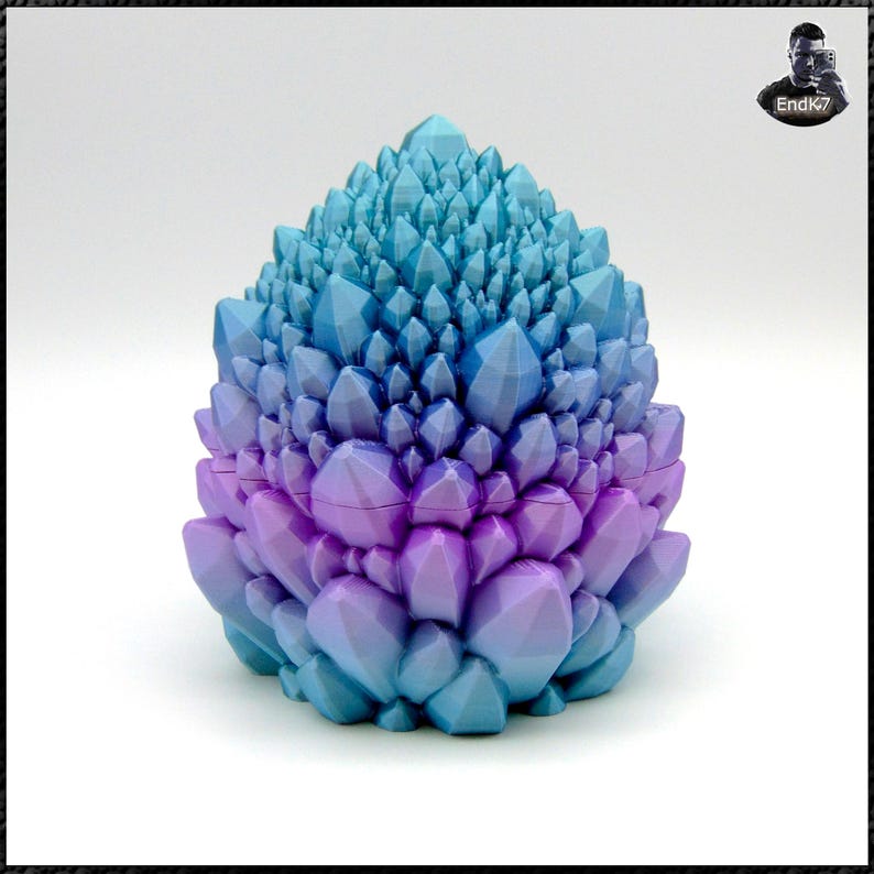 May include: A decorative, geometric object in the shape of a crystal cluster. The object transitions from a blue hue at the top to a purple color at the base. The surface is composed of many individual, pointed facets.