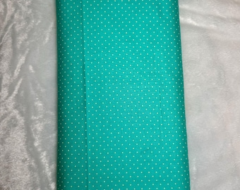 May include: A rolled bolt of teal fabric with a white polka dot pattern. The fabric is a solid teal color with evenly spaced white dots. The fabric is likely cotton or a similar material, suitable for sewing and crafting projects.