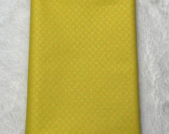 May include: A yellow fabric with a subtle diamond pattern. The fabric is folded in half and appears to be a piece of quilting fabric.
