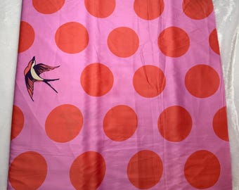 May include: Pink fabric with large orange polka dots and a bird illustration. The fabric is a light pink color with large, evenly spaced orange circles. A bird illustration is on the left side of the fabric.
