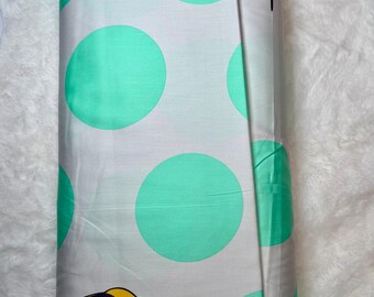 May include: Rolled fabric featuring a repeating pattern of large, light teal circles on a white background. The fabric also has illustrations of birds with yellow, black, and white feathers. The fabric is likely used for sewing or crafting projects.