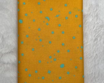 May include: A yellow fabric with a teal blue star and crescent moon pattern.