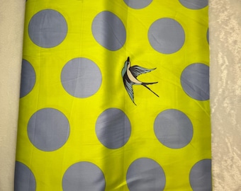 May include: A folded fabric with a bright yellow background and large gray polka dots. A blue and white bird illustration is featured on the fabric. The fabric has a silky sheen.