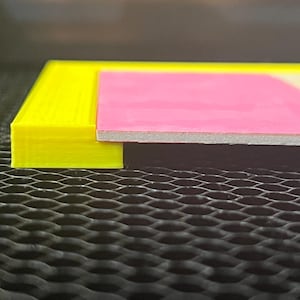 Może przedstawiać: Zbliżenie krawędzi żółtej ramki z różową i białą passe-partout. Ramka jest wykonana z plastiku drukowanego w 3D.
