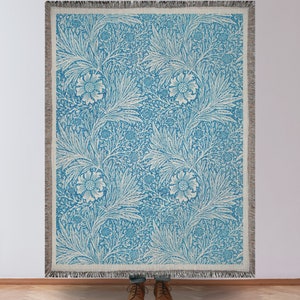Blue William Morris Woven Blanket Being Held in Front of a Blank Wall