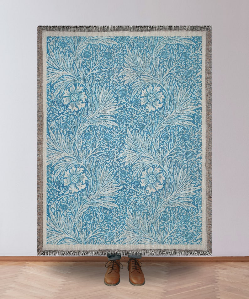Blue William Morris Woven Blanket Being Held in Front of a Blank Wall