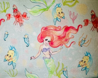 May include: A colorful illustration of Ariel, the Little Mermaid, with red hair and a green tail, swimming in the ocean.  She is surrounded by sea creatures, including a yellow fish, a red crab, and a blue seahorse.