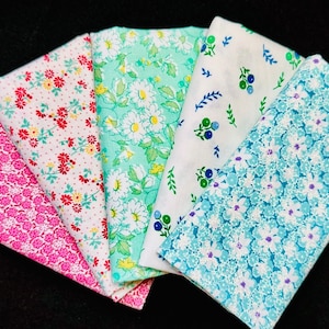 May include: Five fabric swatches with floral patterns. The swatches are in shades of pink, green, blue, and white. The patterns include small flowers, large flowers, and berries.
