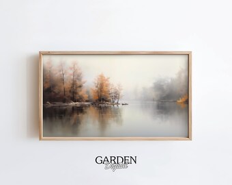 May include: A framed landscape painting depicts a serene lake scene. The artwork features trees with orange and brown foliage reflected in the calm water. The sky is a soft, muted color, and the overall mood is tranquil. The frame is made of light-colored wood. The text "GARDEN Digital" is at the bottom.