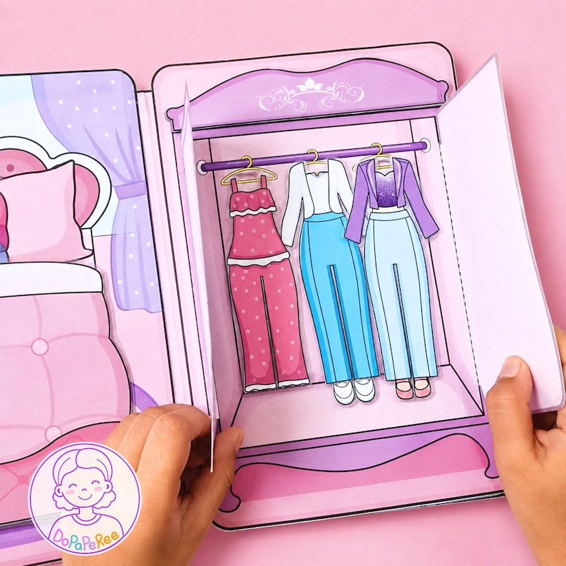 May include: A paper craft set featuring a purple wardrobe with three outfits hanging on a rod: a pink polka dot jumpsuit, a white top with light blue trousers, and a purple jacket with a matching top and light blue trousers, all in a bedroom scene.