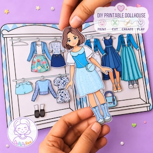 May include: A DIY printable paper doll set featuring a character with brown hair wearing a blue dress and boots. The set includes a wardrobe background with various paper clothing items like jackets, skirts, and dresses in shades of blue and floral patterns.