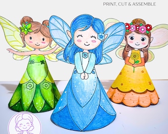 May include: Three colorful paper fairy dolls with wings, each with a unique dress and hairstyle. The fairies are in shades of green, blue, and yellow. The image includes the text "INSTANT DOWNLOAD PRINT, CUT & ASSEMBLE" at the top.