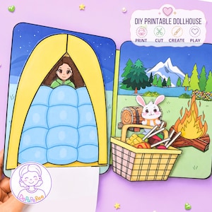 May include: A DIY printable dollhouse set featuring a camping scene with a yellow tent, a person in a blue sleeping bag, a white rabbit, a campfire, and a picnic basket. The text reads DIY PRINTABLE DOLLHOUSE, PRINT, CUT, CREATE, PLAY.