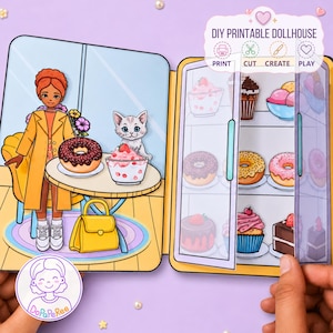 Puede incluir: Un set de casa de muñecas imprimible con una figura de papel, un gato, una mesa con una dona y postre, y un refrigerador lleno de dulces ilustrados como cupcakes, donas y pasteles. El set incluye etiquetas de texto para imprimir, cortar, crear y jugar.