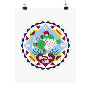 Op de afbeelding: Een kunstafdruk met honkbalthema met een groen personage in een honkbaluniform, met een rode pet en witte strepen. Het ontwerp bevat honkballen, hotdogs, harten en de tekst "Bless This House" in een hartvorm, alles in een cirkelvormig frame.