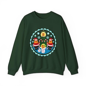 May include: A dark green sweatshirt featuring a circular graphic with a Christmas theme. The graphic includes two figures in Santa hats, candy canes, a Christmas tree, and a central figure with the text "WA WA".