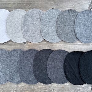 Könnte beinhalten: Ein Farbverlauf von grauen Stoffproben, die von hellgrau bis schwarz reichen, in zwei Reihen mit jeweils acht Proben angeordnet.