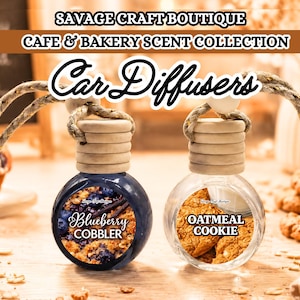 Könnte beinhalten: Zwei Auto-Lufterfrischer mit Holzaufsätzen und Aufhängeschnüren. Einer ist dunkelblau mit dem Text "Blueberry Cobbler", der andere ist klar mit dem Text "Oatmeal Cookie". Der Text "SAVAGE CRAFT BOUTIQUE CAFE & BAKERY SCENT COLLECTION" ist ebenfalls vorhanden.