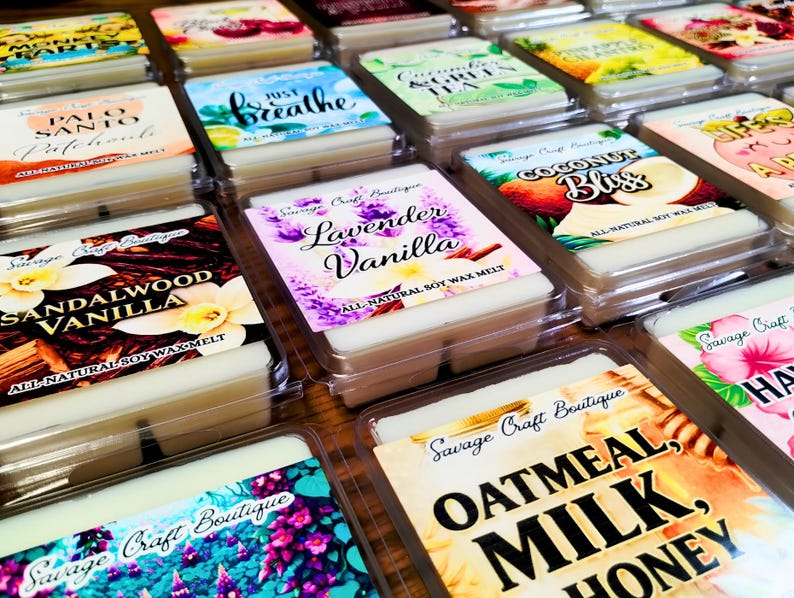 May include: A collection of rectangular wax melts in clear plastic containers, each featuring a label with the Savage Craft Boutique logo and specific scent names like Lavender Vanilla, Sandalwood Vanilla, Oatmeal, Milk, Honey, and Coconut Bliss.