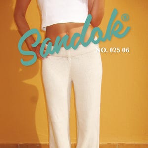 Op de afbeelding: Crèmekleurige broek van geribbelde tricot met wijde pijpen, gecombineerd met turquoise slippers. De afbeelding toont het woord "Sandale" in turquoise script, samen met "NO. 025 06" en "PANTS SIZE XS-XXL". De achtergrond is een effen oranje muur.