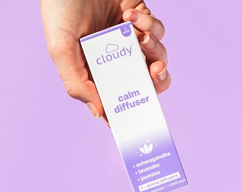 May include: A white box with a purple cloud logo and the text "cloudy" in white. The box says "calm diffuser" and lists the ingredients: ashwagandha, lavender, and jasmine. It also says "3x aroma diffusers with botanicals - 1,800 uses".