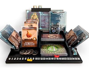 Pode incluir: Um organizador de jogos de tabuleiro preto com vários compartimentos para cartas, fichas e peças de jogo. O organizador tem uma base numerada de 0 a 26. Vários cartões de jogo com ilustrações e texto são visíveis, juntamente com fichas e dados.