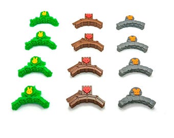 Op de afbeelding: Twaalf miniatuur plastic bruggen met verschillende ontwerpen. Zes bruggen zijn bruin met rode harten en zes bruggen zijn groen met gele konijnen. De bruggen zijn ontworpen voor een bordspel.