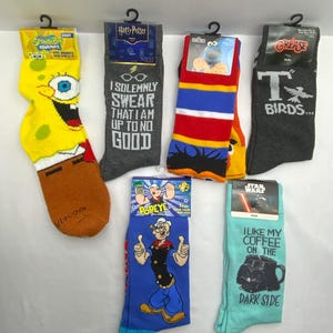 Puede incluir: Calcetines variados con personajes de Bob Esponja, Harry Potter, Cookie Monster, Grease, Popeye y Star Wars. Cada par presenta colores vibrantes e imágenes icónicas, ideales para fans.