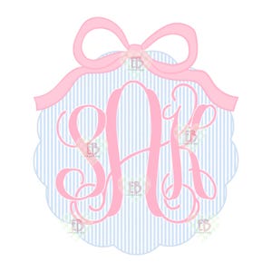 May include: A pink monogram with the letters S, A, and K, set against a blue and white striped background. The monogram is framed by a scalloped edge and topped with a pink bow. The design is on a white background.