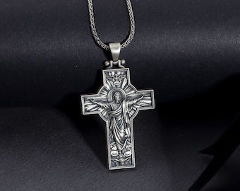 May include: A silver chain necklace with a detailed silver cross pendant featuring a raised image of Jesus Christ. The cross is on a black background.