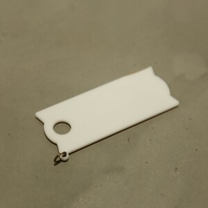 May include: White plastic key tag with a round hole and a small metal loop.