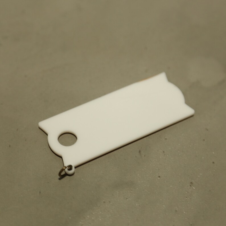 May include: White plastic key tag with a round hole and a small metal loop.