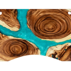 May include: A wooden serving board with a natural wood grain pattern and blue epoxy resin filling the cracks and crevices. The board has a curved edge and two holes on the top.