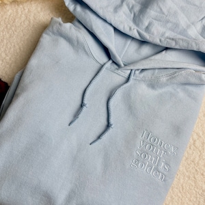 Kuschelweicher Pullover mit Kapuze und einem personalisierten, hochwertigen Stick auf der linken Seite.