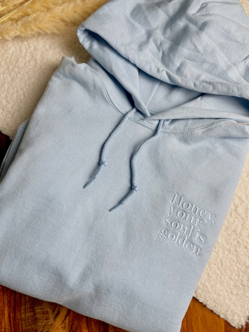Kuschelweicher Pullover mit Kapuze und einem personalisierten, hochwertigen Stick auf der linken Seite.