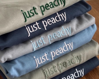 Geborduurd, gepersonaliseerd premium T-shirt van biologisch katoen met de tekst van uw keuze, verkrijgbaar in unisex maten.
