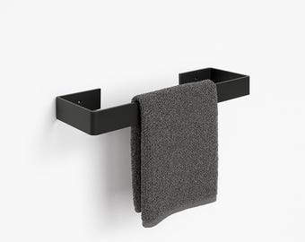 May include: A modern black towel rack with a matching gray towel hanging from it. The rack is mounted on a white wall. The towel is folded and has a soft, textured appearance. The design is minimalist and contemporary.