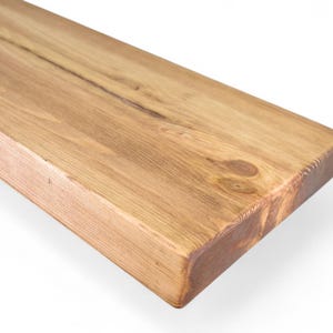 Peut inclure: Gros plan sur une &eacute;tag&egrave;re rectangulaire en bois brun clair. Le grain du bois est visible, avec des n&oelig;uds et des variations naturelles de couleur. Les bords sont carr&eacute;s et l'&eacute;tag&egrave;re semble inachev&eacute;e ou l&eacute;g&egrave;rement teint&eacute;e. L'&eacute;tag&egrave;re est inclin&eacute;e, sur fond blanc.