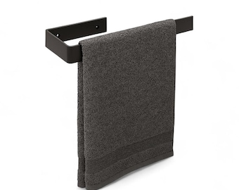 May include: A black metal towel bar with a dark gray towel hanging from it. The towel is folded and has a textured appearance. The towel bar is mounted on a white background.