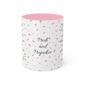 May include: White ceramic mug with a pink interior and rim. The mug displays the text "Pride and Prejudice" in a script font, along with scattered pink petal designs and excerpts from the novel.