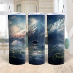 May include: Three stainless steel tumblers with a Japanese landscape design. The design features a mountain, a pagoda, and clouds. Each tumbler has a silver straw and a clear lid. The background is a blurred image of a kitchen.