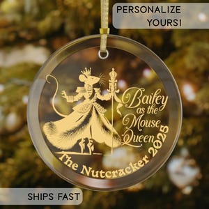 May include: Clear, round Christmas ornament with a gold illustration of a mouse in a queen's attire, holding a scepter. The text "Bailey as the Mouse Queen 2025" and "The Nutcracker" are also in gold. A gold ribbon is attached for hanging.