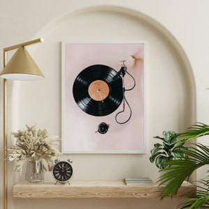 May include: A framed print of a black vinyl record on a turntable with a pink background.
