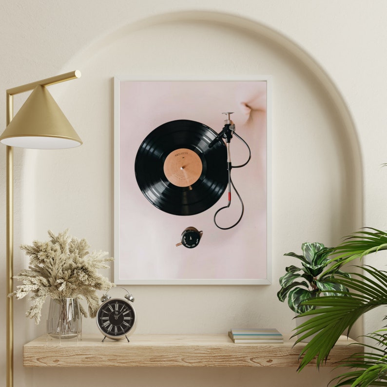 May include: A framed print of a black vinyl record on a turntable with a pink background.
